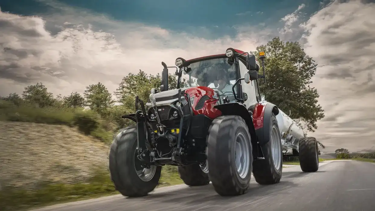 Case IH Farmall 110 A med tankvagn på en landsväg.