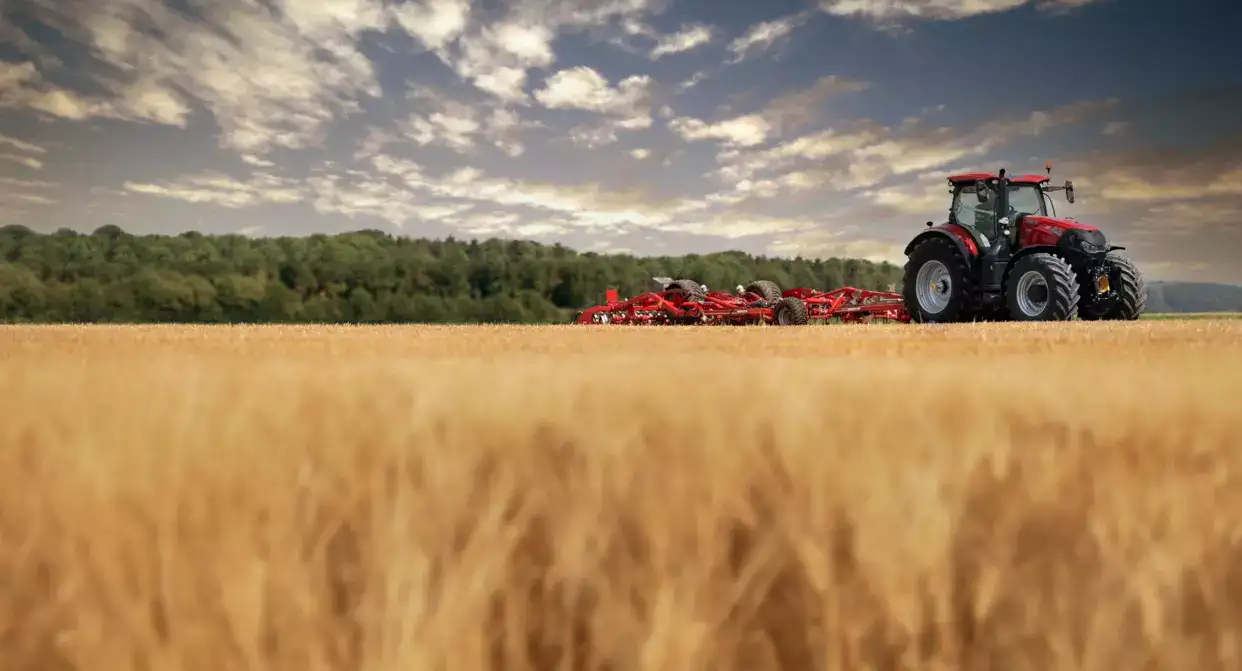 Case IH Optum-traktor med röd kultivator i ett fält; exakt modell och utförande framgår inte.