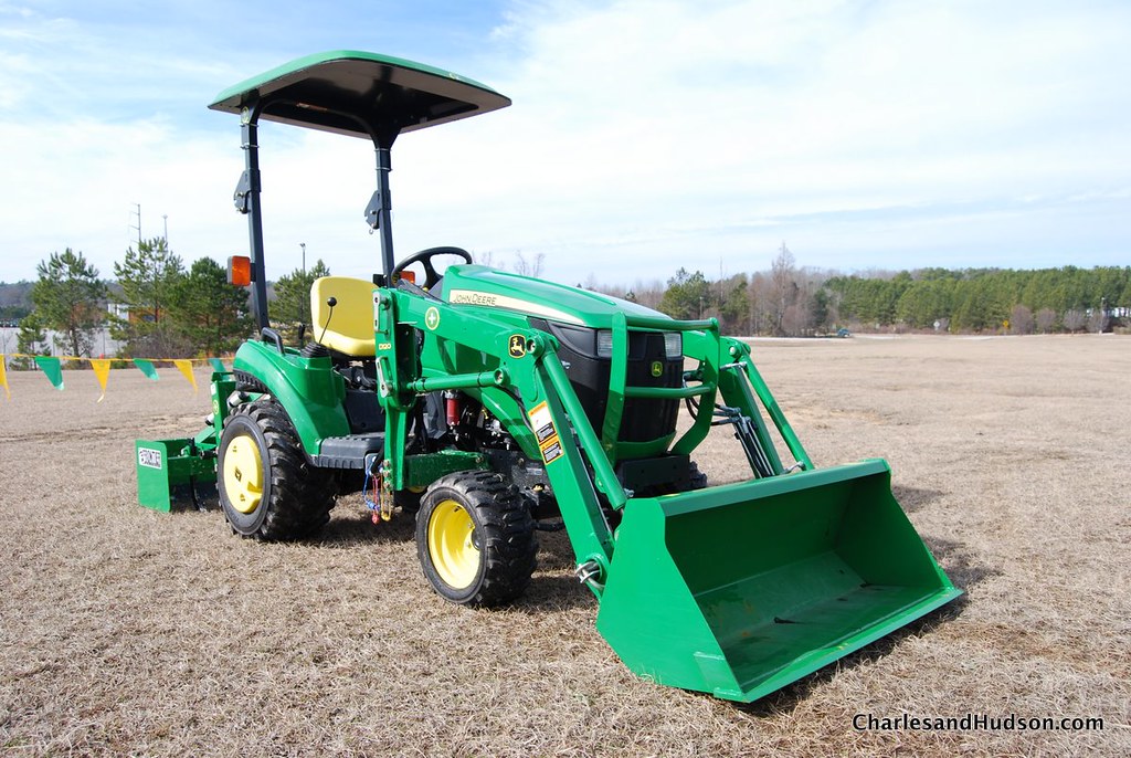 John Deere 1026R med ROPS-tak, frontlastare och jordfräs vid fabrikstest.