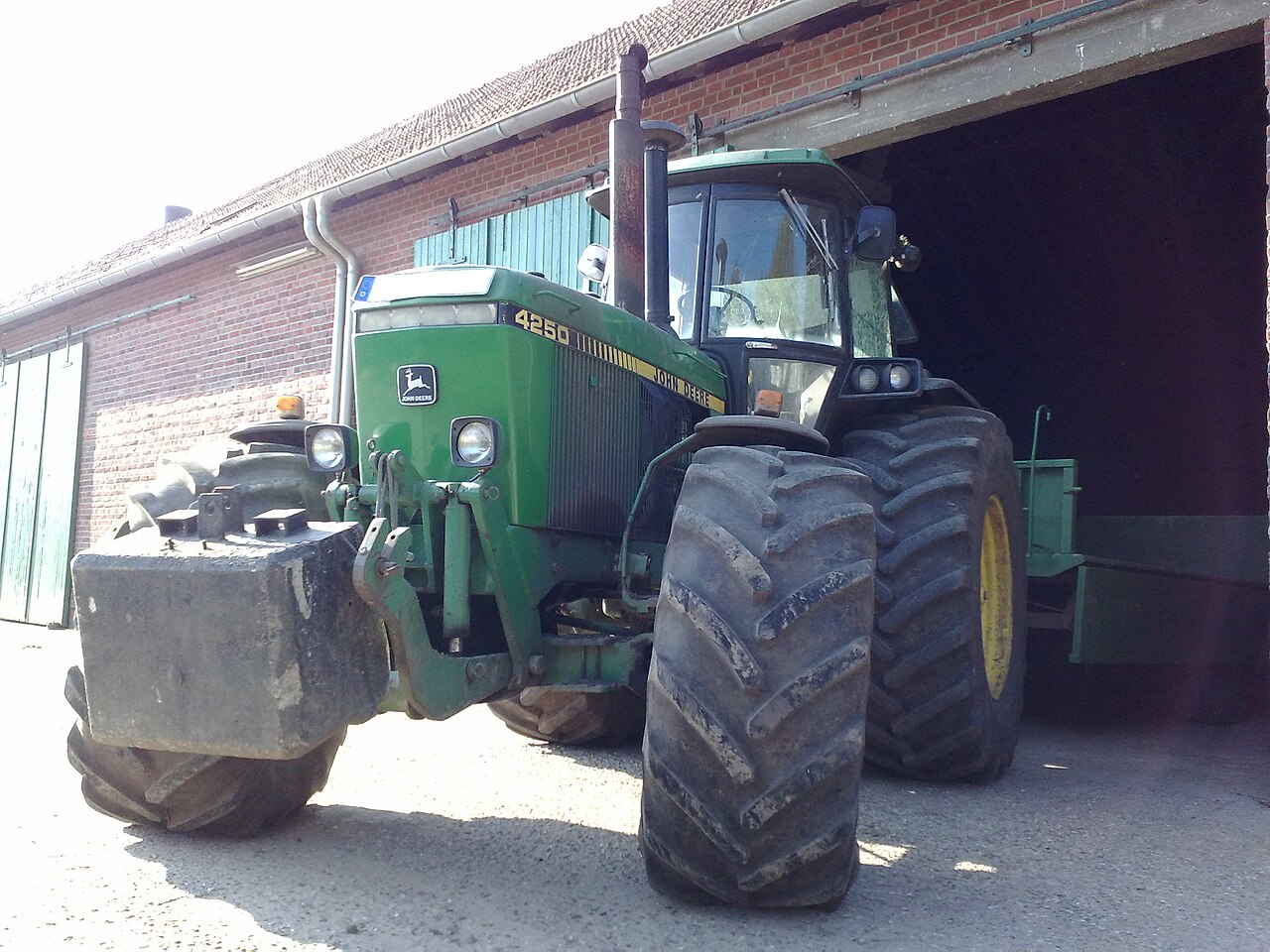 John Deere 4250 vid en lantbruksbyggnad.