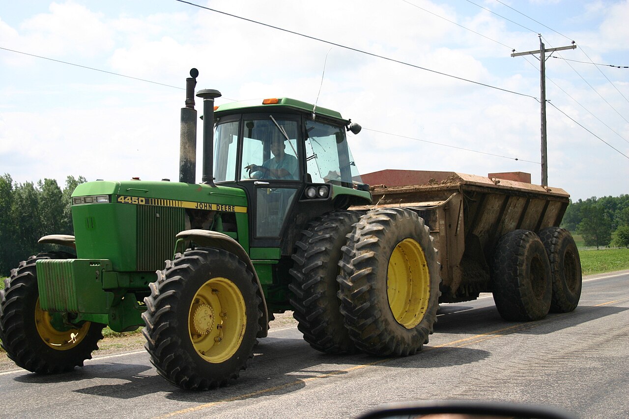 John Deere 4450 med gödselspridare på en väg i New York.