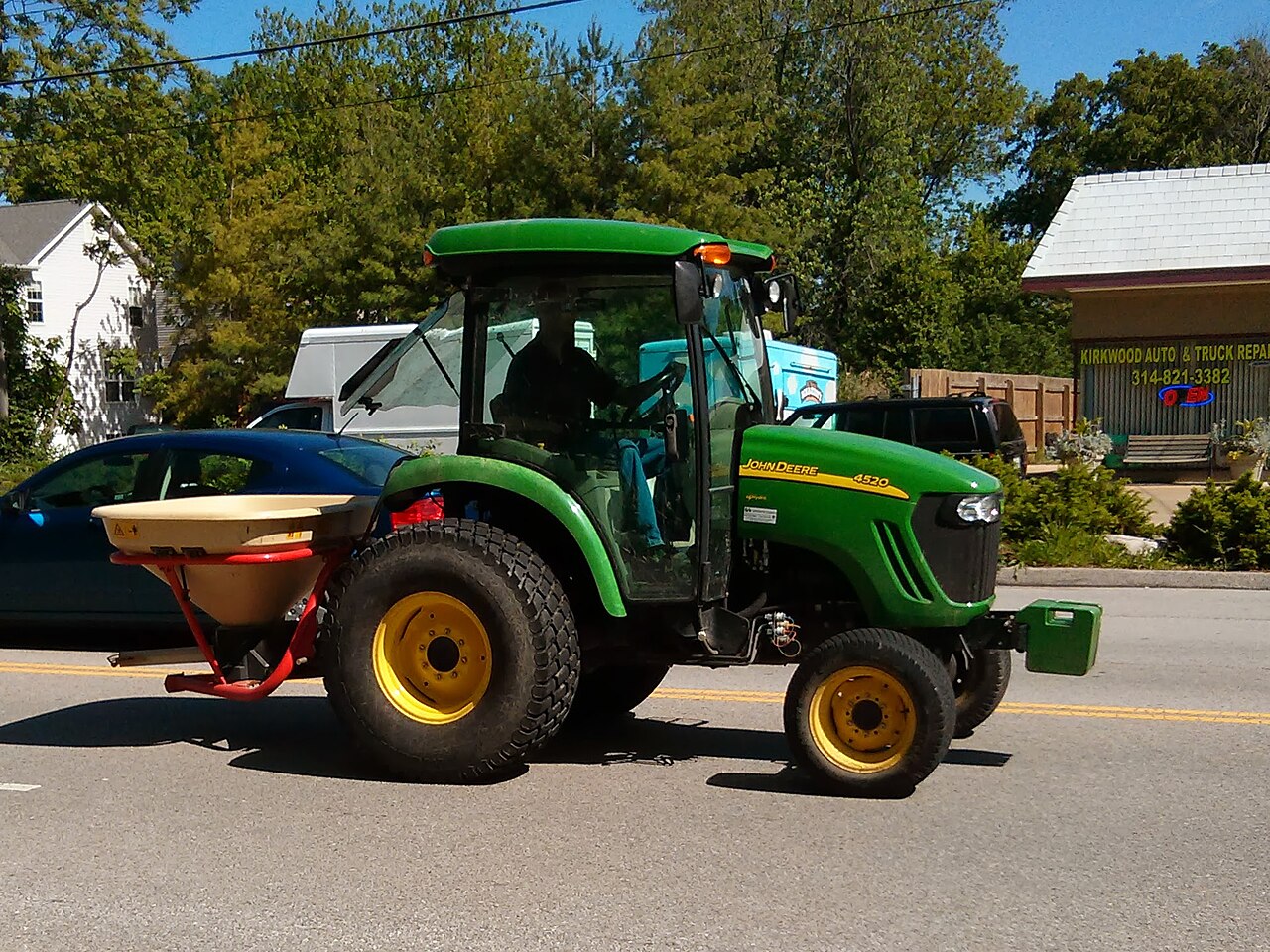 John Deere 4520 Compact Utility Tractor med monterat spridningsredskap.