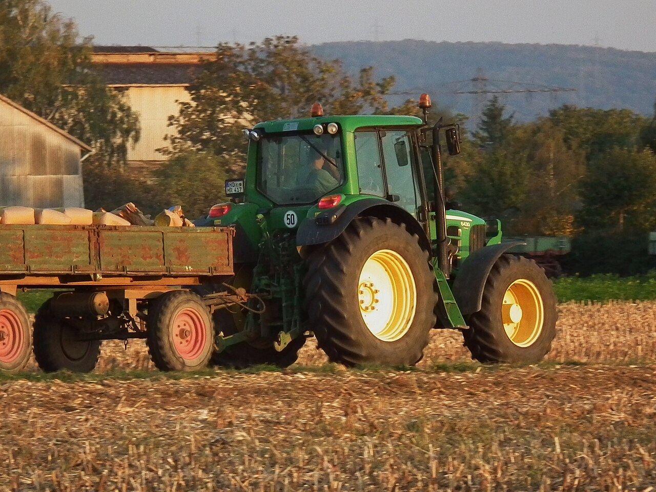 John Deere 6430 Premium med släp på ett fält.
