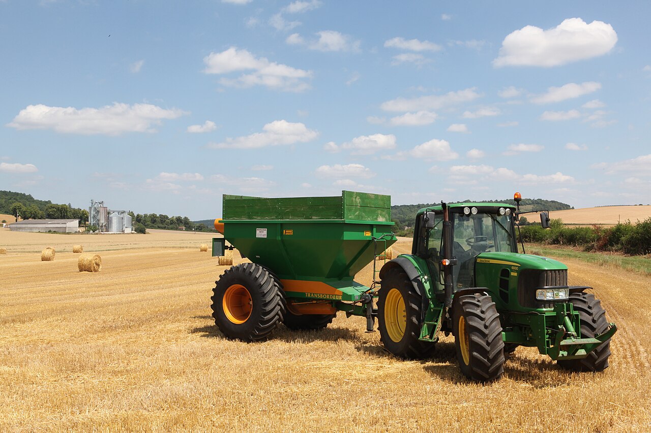 John Deere 6930 Premium med spannmålsvagn på ett skördat fält.