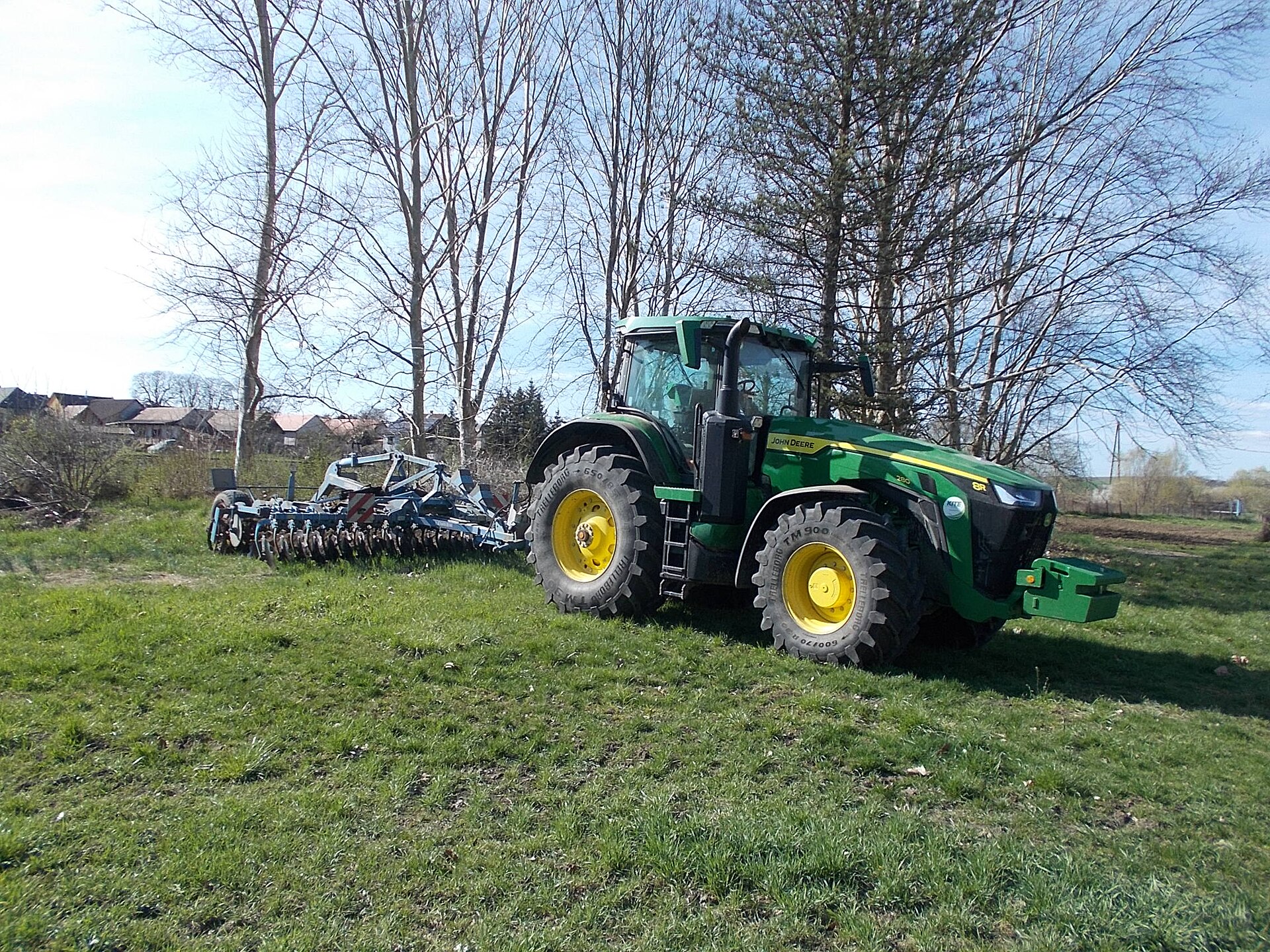 John Deere med synliga 8R- och 280-märkningar och ett redskap baktill.