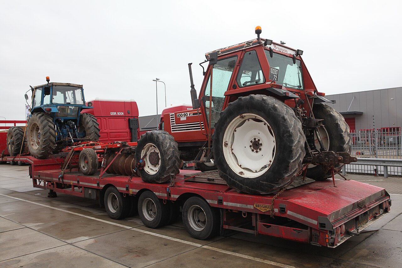 FiatAgri 100-90 DT på transportvagn, sedd snett bakifrån; 100-90 DT-märkningen på huven är synlig.