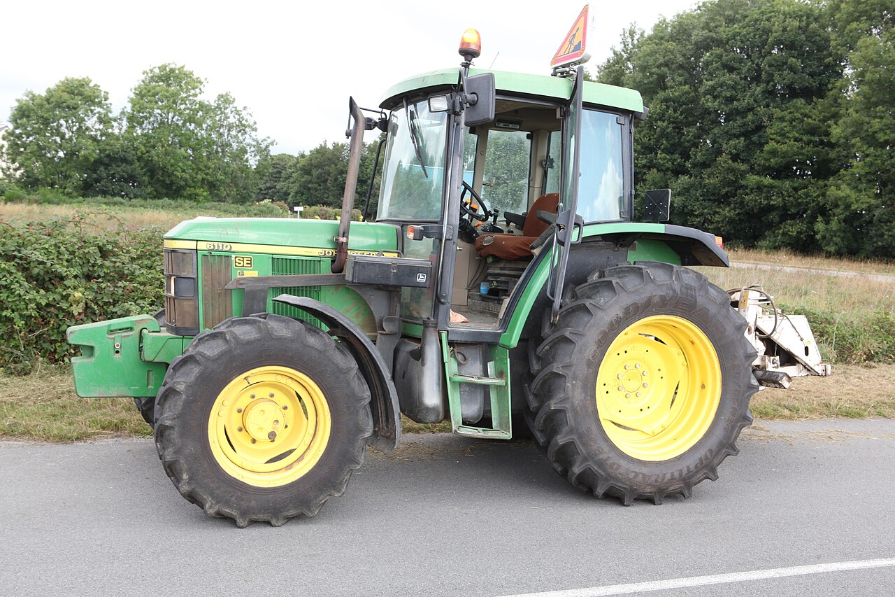 Grön John Deere 6110 SE-traktor med hytt, fotograferad från sidan.