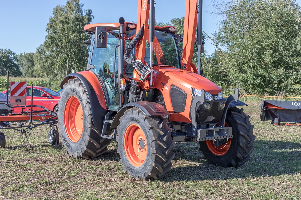 Kubota M5-112 med hytt och frontlastare på gräsmark.