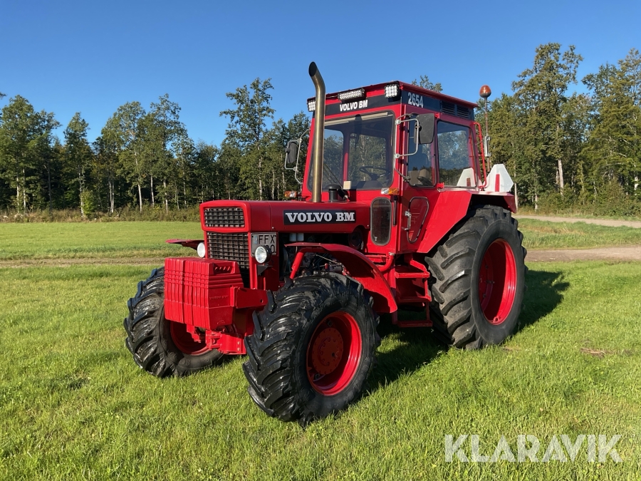 Röd Volvo BM 2654 från 1982 på ett gräsfält; modellnumret 2654 syns på hyttaket.
